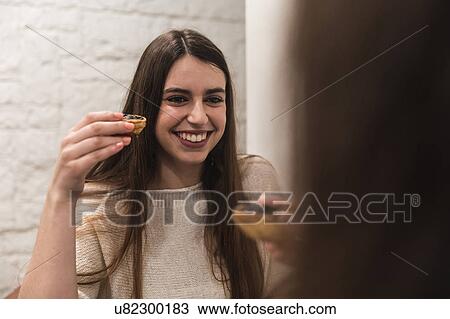 Stock Image - Woman holding pastry smiling. Fotosearch