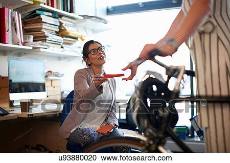 Stock Image - Woman in office handing note to colleague. Fotosearch