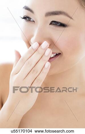 Picture - Woman laughing with hand covering mouth. Fotosearch