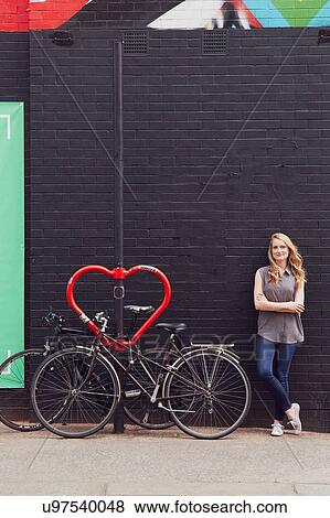 Woman leaning against wall beside bicycle stand View Large Photo Image Stock Photo - Woman leaning against wall beside bicycle stand. Fotosearch
