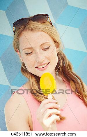 Stock Image - Woman looking down at ice lolly. Fotosearch