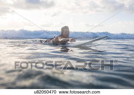 Stock Image - Woman paddling on surfboard in sea, Nosara, Guanacaste Province, Costa Rica. Fotosearch