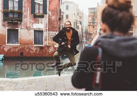 Woman photographing man jumping by canal, Venice, Italy View Large Photo Image Stock Image - Woman photographing man jumping by canal, Venice, Italy. Fotosearch