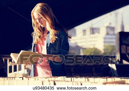 Stock Photography - Woman reading at book stall, London, UK. Fotosearch