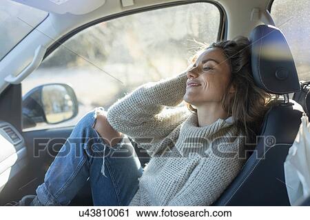 Stock Image - Woman reclining in car front seat. Fotosearch
