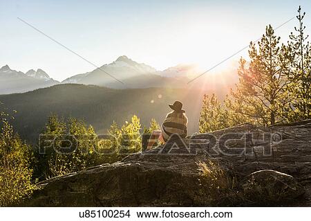 Woman sitting on rocks, looking at view, rear view, Squamish, British Columbia, Canada View Large Photo Image Picture - Woman sitting on rocks, looking at view, rear view, Squamish, British Columbia, Canada. Fotosearch