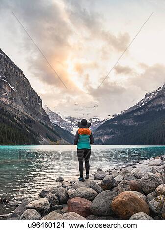 Woman standing at edge of lake, looking at view, rear view, Lake Louise, Alberta, Canada View Large Photo Image Picture - Woman standing at edge of lake, looking at view, rear view, Lake Louise, Alberta, Canada. Fotosearch