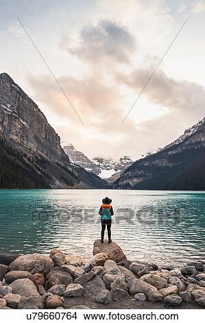 Picture - Woman standing on rock, looking at lake view, rear view, Lake Louise, Alberta, Canada. Fotosearch