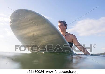 Picture - Woman straddling surfboard in sea, Nosara, Guanacaste Province, Costa Rica. Fotosearch