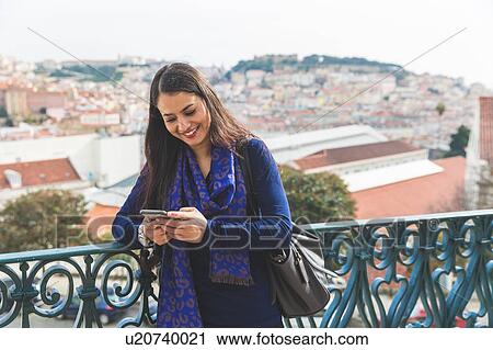 Stock Image - Woman texting on smartphone, Lisbon, Portugal. Fotosearch