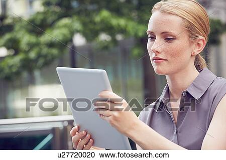 Stock Image - Woman using digital tablet, London, UK. Fotosearch