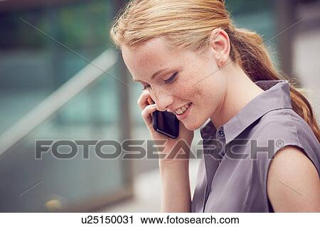 Stock Image - Woman using mobile phone in street, London, UK. Fotosearch