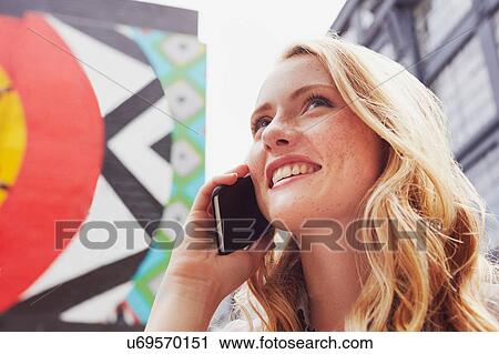 Stock Image - Woman using mobile phone in street, London, UK. Fotosearch