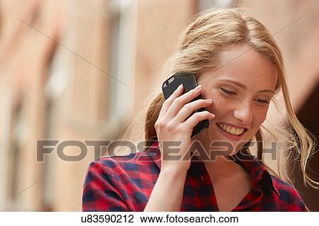 Stock Image - Woman using mobile phone in street, London, UK. Fotosearch
