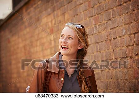 Stock Image - Woman walking along brick wall, London, UK. Fotosearch