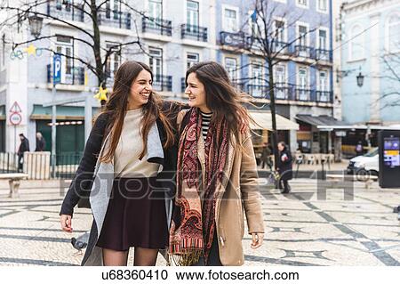 Stock Image - Woman walking arm and arm in city, Lisbon, Portugal. Fotosearch