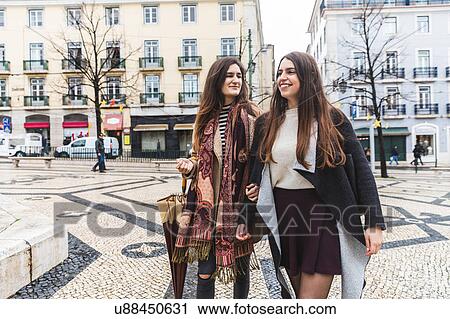 Stock Image - Woman walking arm and arm in city, Lisbon, Portugal. Fotosearch