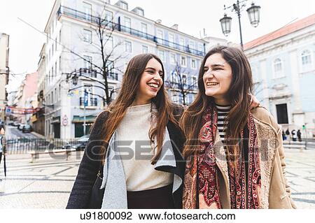 Stock Image - Woman walking arm and arm in city, Lisbon, Portugal. Fotosearch