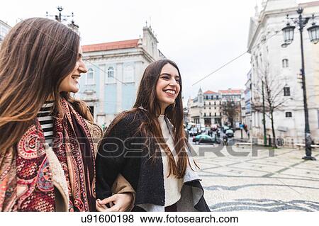 Stock Photo - Woman walking arm and arm in city, Lisbon, Portugal. Fotosearch