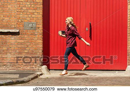Woman walking past red door, London, UK View Large Photo Image Stock Photo - Woman walking past red door, London, UK. Fotosearch