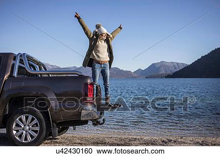 Woman with arms open standing on pick up at lakeside in Bavarian Alps View Large Photo Image Stock Image - Woman with arms open standing on pick up at lakeside in Bavarian Alps. Fotosearch