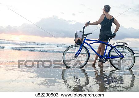 Woman with bicycle looking out from beach at sunset, Nosara, Guanacaste Province, Costa Rica View Large Photo Image Stock Image - Woman with bicycle looking out from beach at sunset, Nosara, Guanacaste Province, Costa Rica. Fotosearch