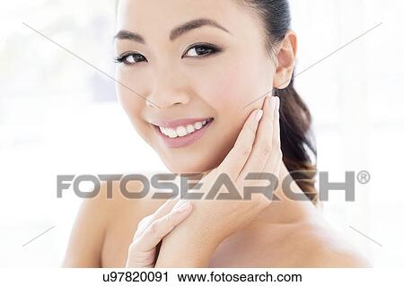 Stock Image - Woman with hands touching face. Fotosearch