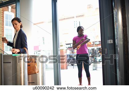 Stock Image - Women arriving at entrance to work. Fotosearch