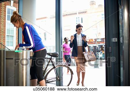 Stock Photo - Women arriving at entrance to work. Fotosearch