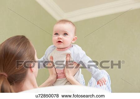 Stock Photo - Women holding up baby daughter. Fotosearch