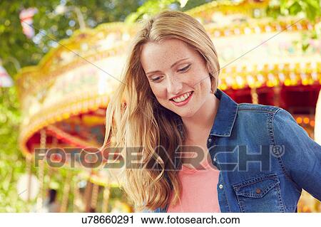 Stock Image - Women smiling, carousel in background, London, UK. Fotosearch