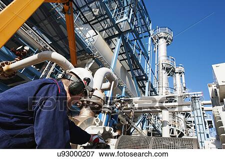 Worker checking pipework on an oil and gas refinery View Large Photo Image Stock Photo - Worker checking pipework on an oil and gas refinery. Fotosearch