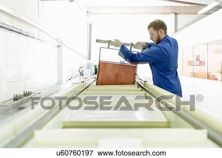 Stock Photo - Worker hand processing metal board in electronics factory. Fotosearch