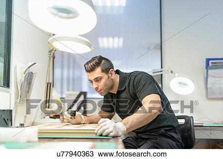 Stock Image - Worker inspecting circuit boards in electronics factory. Fotosearch
