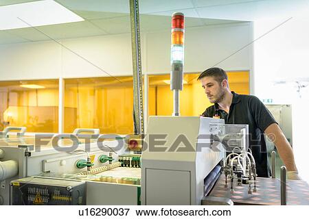 Stock Photo - Worker operating circuit board processing machine in electronics factory. Fotosearch