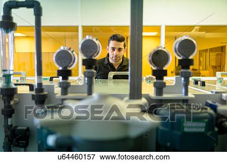 Stock Photo - Worker operating circuit board processing machine in electronics factory. Fotosearch