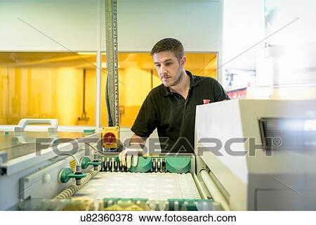 Stock Photo - Worker operating circuit board processing machine in electronics factory. Fotosearch