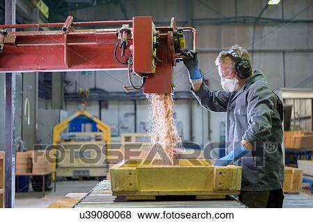 Stock Photo - Worker pouring sand into mould in precision casting factory. Fotosearch