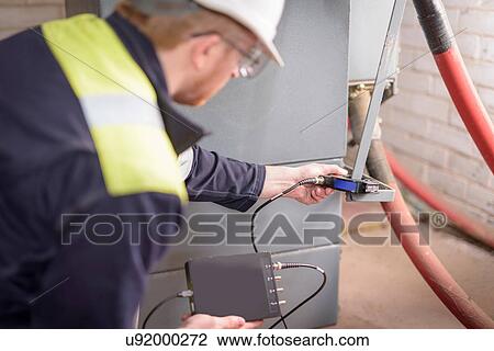 Stock Image - Worker testing transformers in electricity substation. Fotosearch