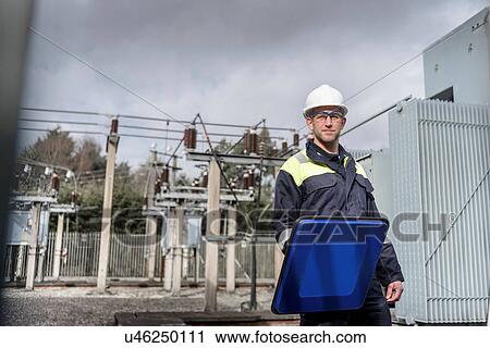 Stock Image - Worker using partial discharge detector in electricity substation. Fotosearch
