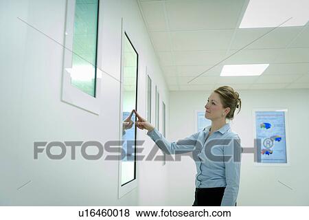 Stock Photo - Worker using wall touch screen. Fotosearch