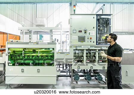 Stock Photograph - Worker with circuit board processing machine in electronics factory. Fotosearch