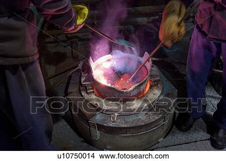 Picture - Workers stirring molten aluminium alloy in precision casting factory. Fotosearch