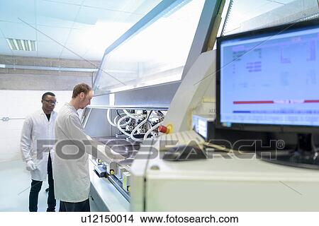 Picture - Workers using automated cutting machine to cut circuit boards in electronics factory. Fotosearch