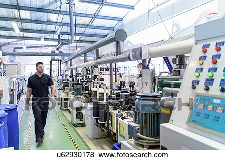 Stock Photo - Workers with circuit board processing machine in electronics factory. Fotosearch