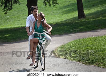 Young couple riding bicycle through park, Turin, Piedmont, Italy View Large Photo Image Stock Photograph - Young couple riding bicycle through park, Turin, Piedmont, Italy. Fotosearch
