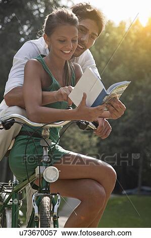 Young couple sitting on bicycle, looking at guidebook, Turin, Piedmont, Italy View Large Photo Image Stock Photo - Young couple sitting on bicycle, looking at guidebook, Turin, Piedmont, Italy. Fotosearch