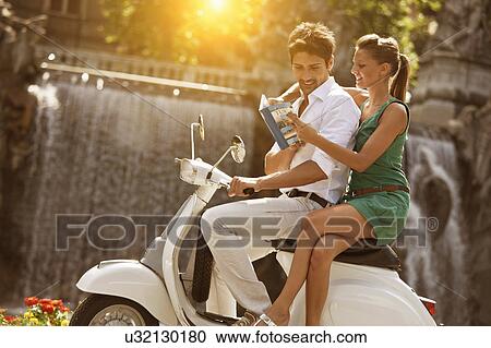 Young couple sitting on scooter, looking at guidebook, Turin, Piedmont, Italy View Large Photo Image Stock Image - Young couple sitting on scooter, looking at guidebook, Turin, Piedmont, Italy. Fotosearch