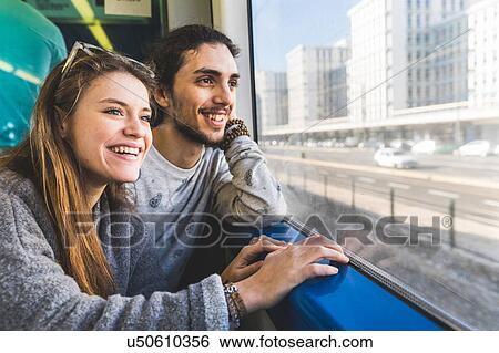 Stock Photograph - Young couple, sitting on train, looking out of window, Lisbon, Portugal. Fotosearch