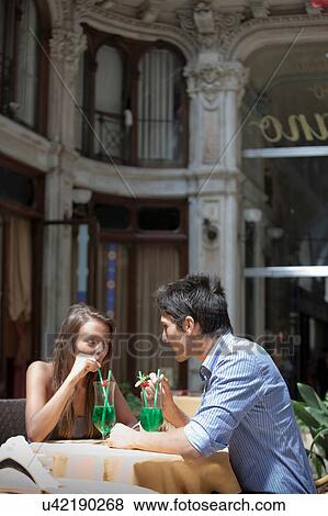Stock Photo - Young couple sitting outside cafe, drinking cocktails, Turin, Piedmont, Italy. Fotosearch